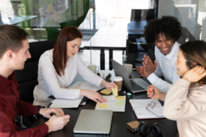 Grupo de amigos sorrindo e conversando e estudando em uma mesa para alcançar a proficiência em inglês